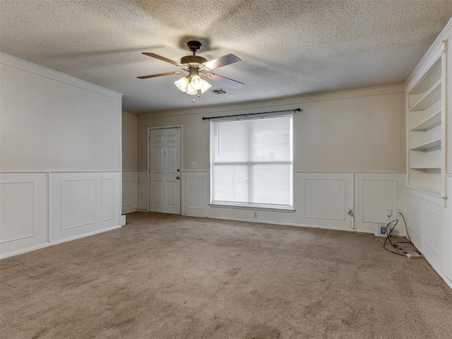 4113 Clendon Way, Del City, OK 73115 - carpeted empty room with a decorative wall, a ceiling fan, a wainscoted wall, a textured ceiling, and crown molding