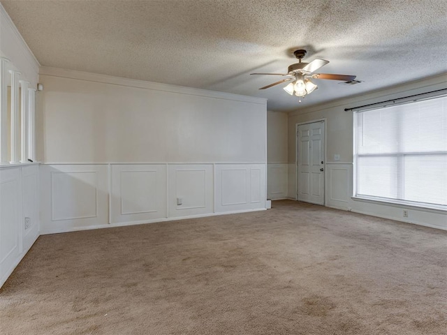 4113 Clendon Way, Del City, OK 73115 - spare room with ceiling fan, a decorative wall, a textured ceiling, light colored carpet, and a wainscoted wall