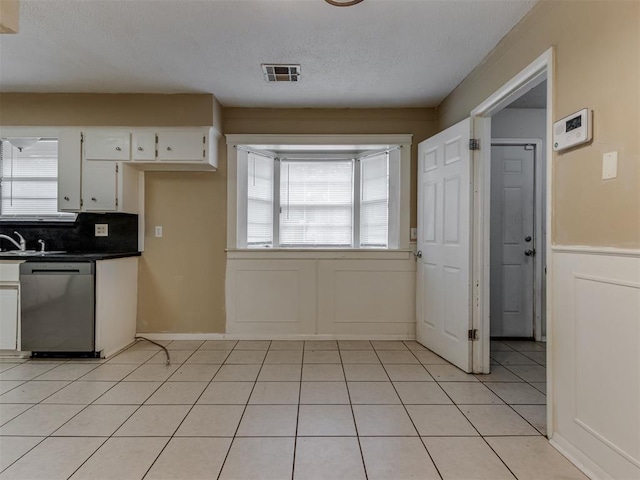 4113 Clendon Way, Del City, OK 73115 - kitchen featuring stainless steel dishwasher, white cabinetry, dark countertops, light tile patterned floors, and backsplash
