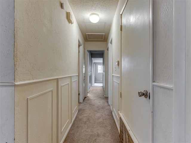 4113 Clendon Way, Del City, OK 73115 - hallway featuring light colored carpet, a textured wall, a textured ceiling, a decorative wall, and a wainscoted wall