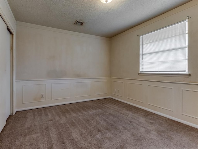 4113 Clendon Way, Del City, OK 73115 - unfurnished room featuring a decorative wall, a textured ceiling, carpet flooring, and a wainscoted wall