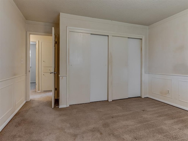 4113 Clendon Way, Del City, OK 73115 - unfurnished bedroom with carpet floors, a closet, wainscoting, a decorative wall, and a textured ceiling