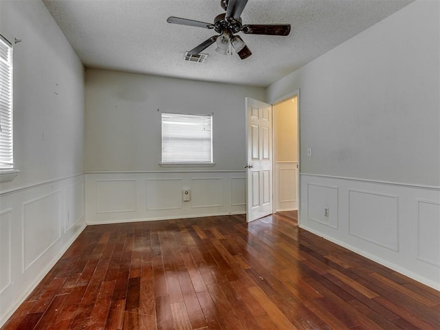 4113 Clendon Way, Del City, OK 73115 - empty room with hardwood / wood-style floors, a textured ceiling, a ceiling fan, wainscoting, and a decorative wall