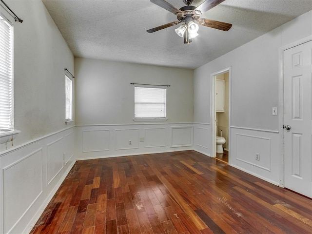 4113 Clendon Way, Del City, OK 73115 - spare room featuring dark wood finished floors, ceiling fan, a wainscoted wall, a decorative wall, and a textured ceiling
