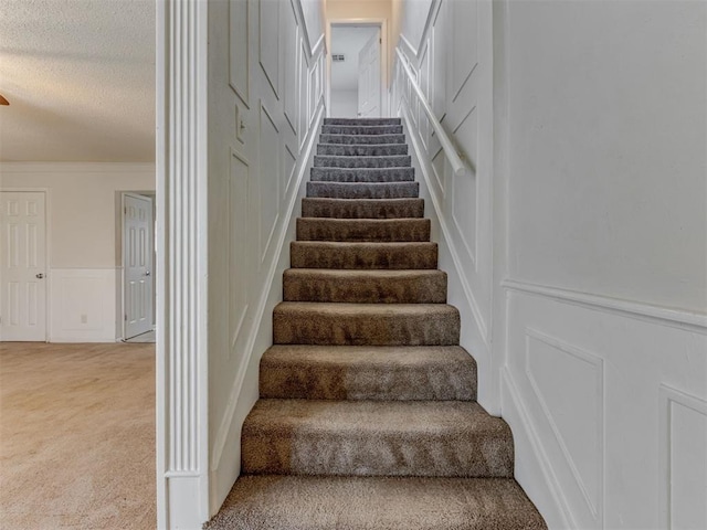 4113 Clendon Way, Del City, OK 73115 - stairway with a decorative wall, carpet flooring, a textured ceiling, and wainscoting