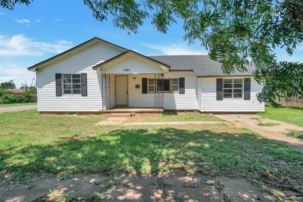 1301 N Crain St, Altus, OK 73521 - ranch-style house featuring covered porch, a front yard, and roof with shingles