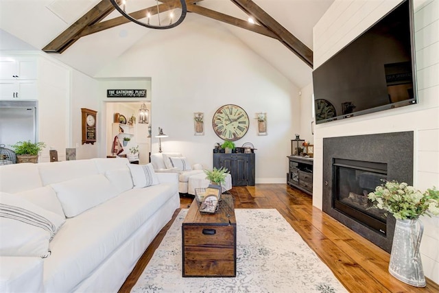 209 Pont Julienn Ct, Edmond, OK 73034 - living area featuring high vaulted ceiling, beamed ceiling, wood finished floors, a glass covered fireplace, and a chandelier