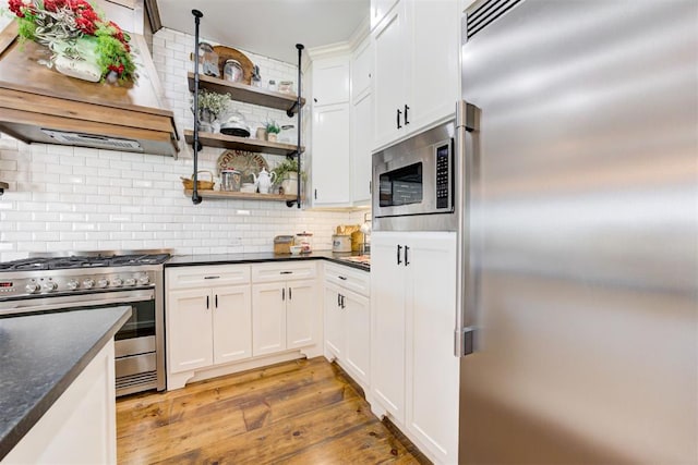209 Pont Julienn Ct, Edmond, OK 73034 - kitchen with built in appliances, range hood, open shelves, tasteful backsplash, and white cabinets