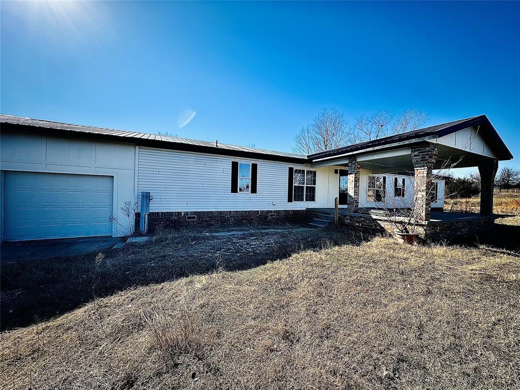 2099 County Road 1244, Tuttle, OK 73089 - back of property featuring an attached garage and covered porch