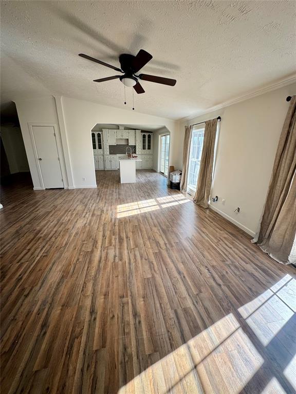 2099 County Road 1244, Tuttle, OK 73089 - unfurnished living room featuring a textured ceiling, dark wood-type flooring, ceiling fan, and arched walkways