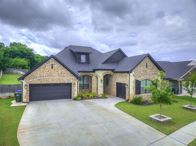 210 Bulverde Dr, Norman, OK 73069 - french country home featuring a shingled roof, a garage, concrete driveway, and stone siding