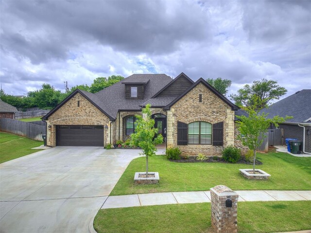 210 Bulverde Dr, Norman, OK 73069 - french country home featuring an attached garage, concrete driveway, brick siding, roof with shingles, and stone siding