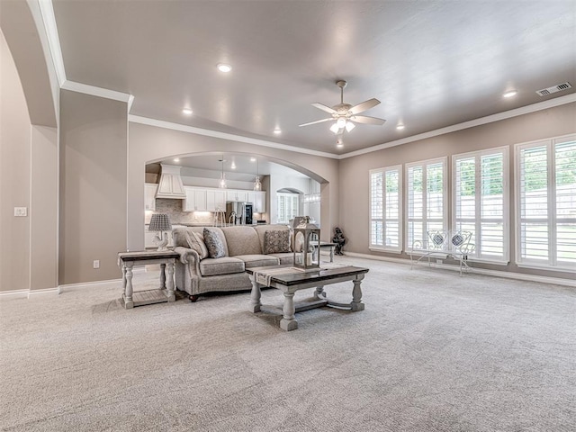 210 Bulverde Dr, Norman, OK 73069 - living area featuring arched walkways, light carpet, healthy amount of natural light, crown molding, and a ceiling fan
