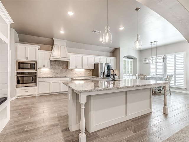 210 Bulverde Dr, Norman, OK 73069 - kitchen featuring appliances with stainless steel finishes, white cabinetry, arched walkways, light wood-type flooring, and recessed lighting