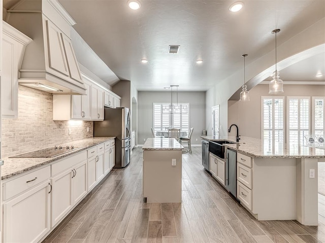 210 Bulverde Dr, Norman, OK 73069 - kitchen featuring a center island with sink, stainless steel appliances, decorative backsplash, hanging light fixtures, and white cabinets