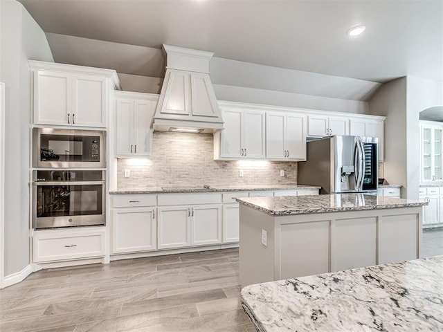 210 Bulverde Dr, Norman, OK 73069 - kitchen featuring black appliances, vaulted ceiling, white cabinetry, decorative backsplash, and custom range hood