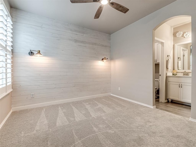 210 Bulverde Dr, Norman, OK 73069 - empty room featuring ceiling fan, wooden walls, arched walkways, and carpet floors
