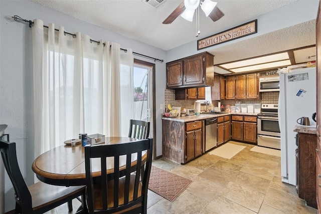 809 N Southminster St, Moore, OK 73160 - kitchen with appliances with stainless steel finishes, backsplash, ceiling fan, a textured ceiling, and light countertops
