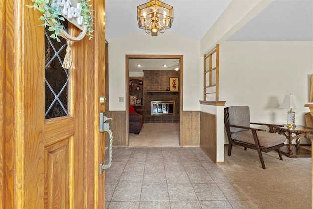 717 Maple St, Weatherford, OK 73096 - entryway featuring light carpet, a wainscoted wall, a chandelier, vaulted ceiling, and a brick fireplace