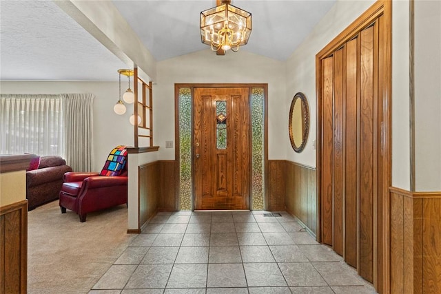 717 Maple St, Weatherford, OK 73096 - foyer entrance with a wainscoted wall, lofted ceiling, a chandelier, wooden walls, and light tile patterned flooring