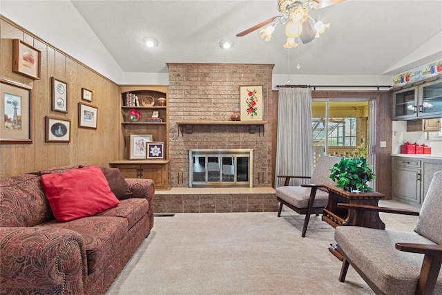 717 Maple St, Weatherford, OK 73096 - carpeted living area featuring vaulted ceiling, ceiling fan, built in features, a fireplace, and wood walls