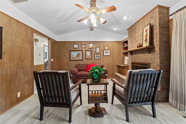 717 Maple St, Weatherford, OK 73096 - living room featuring lofted ceiling, wooden walls, a ceiling fan, a fireplace, and light colored carpet