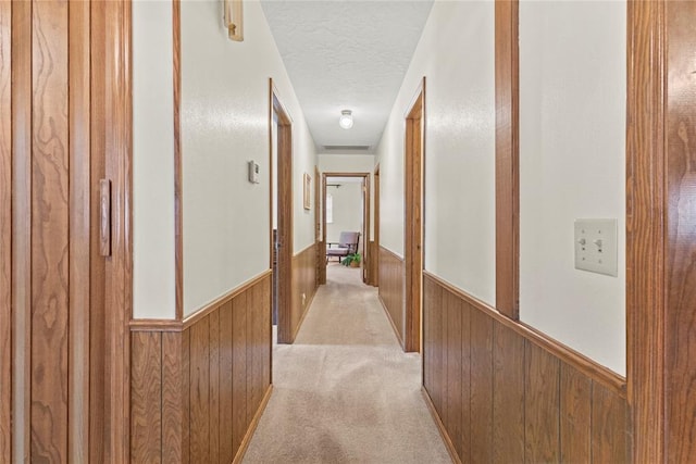 717 Maple St, Weatherford, OK 73096 - hallway with wainscoting, wooden walls, a textured ceiling, and light carpet