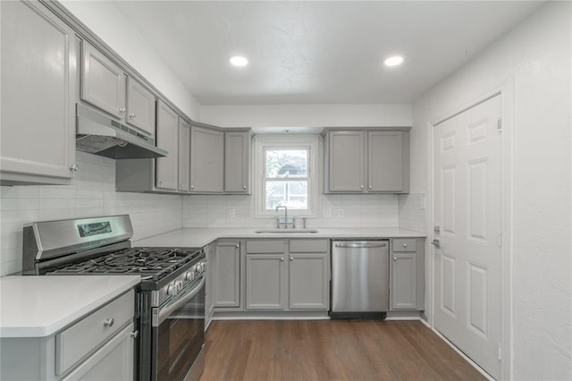 933 SW 50th St, Oklahoma City, OK 73109 - kitchen with appliances with stainless steel finishes, gray cabinetry, under cabinet range hood, dark wood-type flooring, and recessed lighting