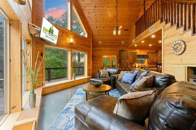 232 Orange Grove Rd, Broken Bow, OK 74728 - living room with finished concrete floors, wooden walls, plenty of natural light, high vaulted ceiling, and a ceiling fan