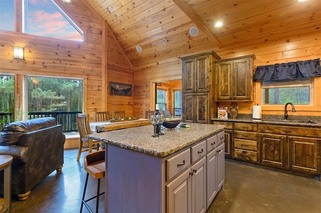 232 Orange Grove Rd, Broken Bow, OK 74728 - kitchen featuring finished concrete floors, wood walls, a breakfast bar area, wood ceiling, and a center island