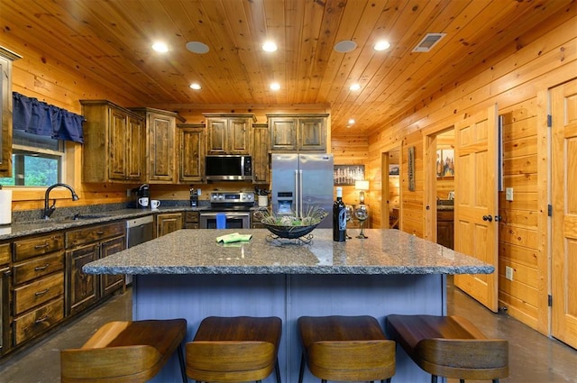 232 Orange Grove Rd, Broken Bow, OK 74728 - kitchen with stainless steel appliances, finished concrete flooring, recessed lighting, a kitchen island, and wooden walls