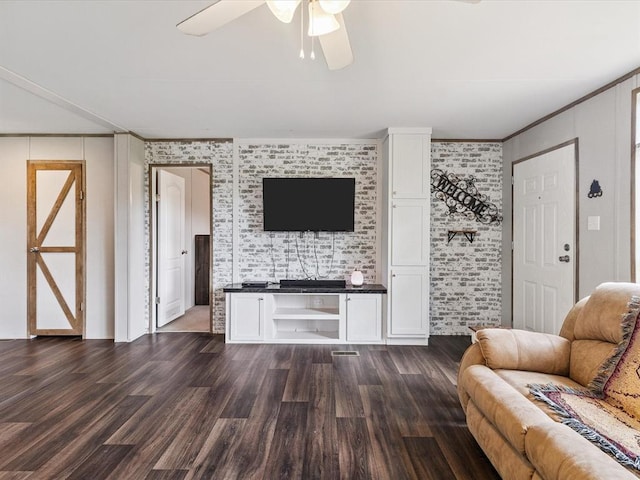 living room featuring dark wood finished floors, ornamental molding, a ceiling fan, and brick wall