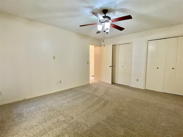 223 E Lincoln Ave, Edmond, OK 73034 - unfurnished bedroom featuring two closets, carpet floors, a ceiling fan, and a textured ceiling