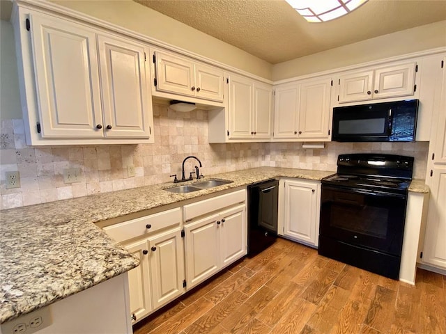 223 E Lincoln Ave, Edmond, OK 73034 - kitchen with black appliances, light stone counters, decorative backsplash, light wood finished floors, and a textured ceiling