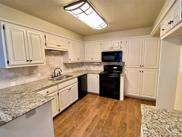 223 E Lincoln Ave, Edmond, OK 73034 - kitchen with black appliances, wood finished floors, white cabinetry, and a textured ceiling