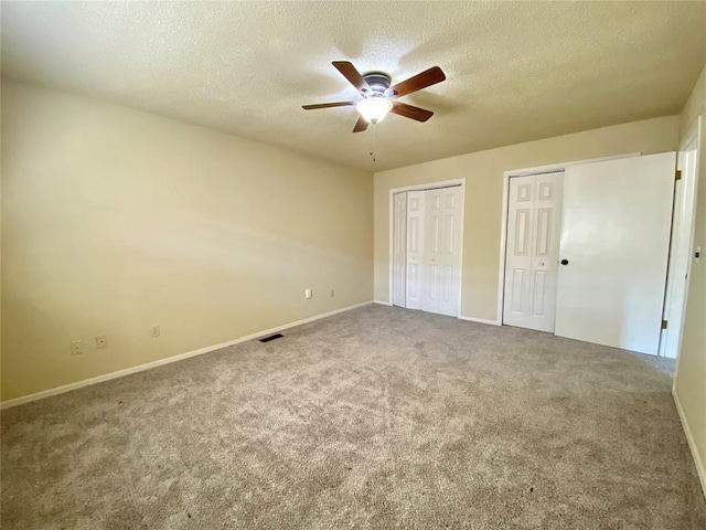 223 E Lincoln Ave, Edmond, OK 73034 - unfurnished bedroom with multiple closets, a textured ceiling, carpet floors, and ceiling fan