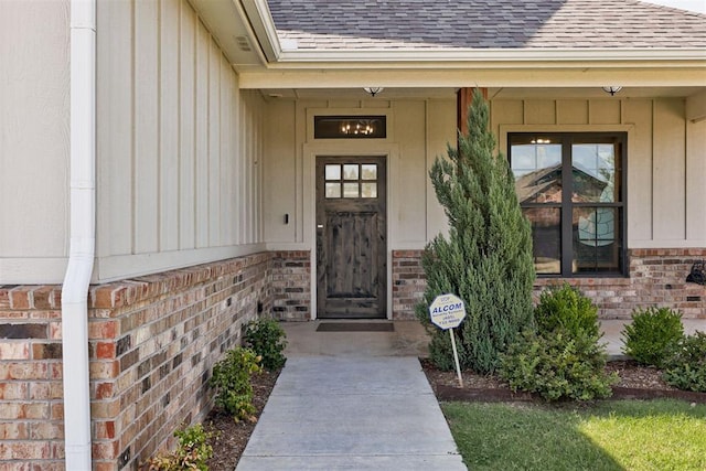 2408 NW 179th St, Edmond, OK 73012 - view of exterior entry with a shingled roof, brick siding, board and batten siding, and covered porch