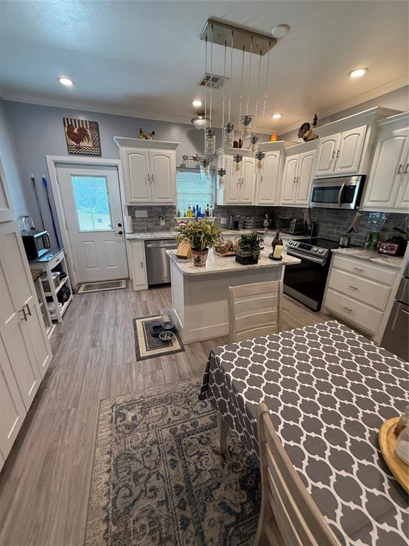 105967 S Rolling Hills Dr, Meeker, OK 74855 - kitchen featuring stainless steel appliances, tasteful backsplash, light wood-style flooring, a center island, and white cabinets