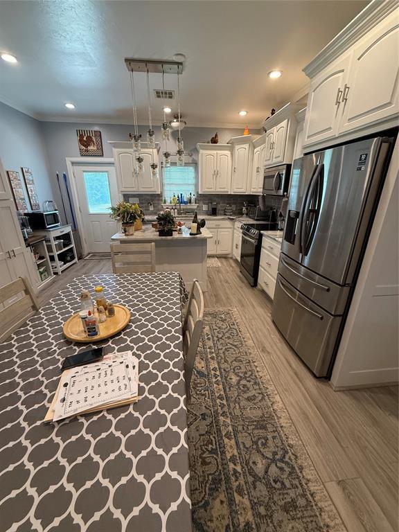 105967 S Rolling Hills Dr, Meeker, OK 74855 - kitchen featuring appliances with stainless steel finishes, light wood finished floors, backsplash, crown molding, and pendant lighting