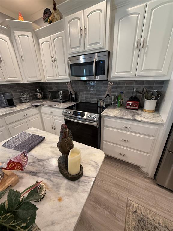 105967 S Rolling Hills Dr, Meeker, OK 74855 - kitchen with stainless steel appliances, white cabinetry, backsplash, and light wood-type flooring