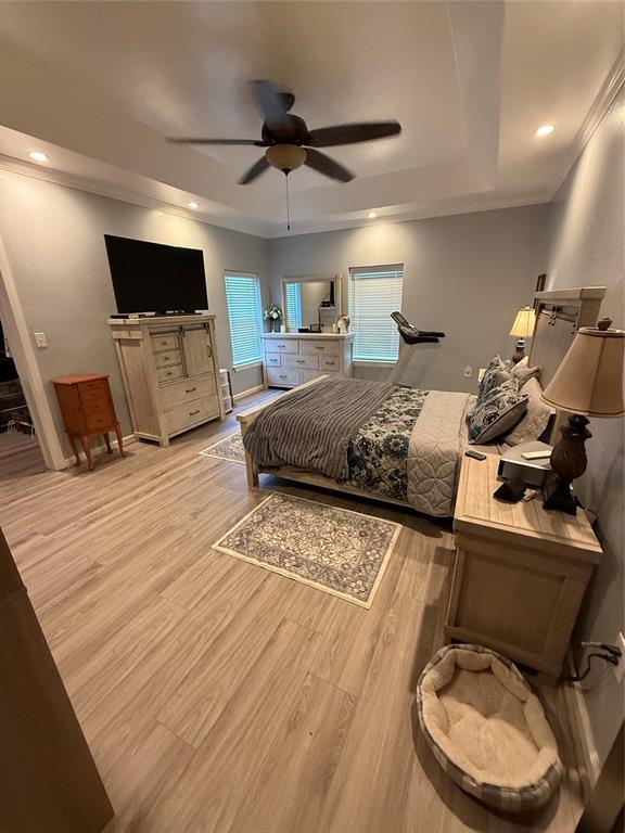 105967 S Rolling Hills Dr, Meeker, OK 74855 - bedroom featuring a tray ceiling, light wood-style floors, ornamental molding, ceiling fan, and recessed lighting