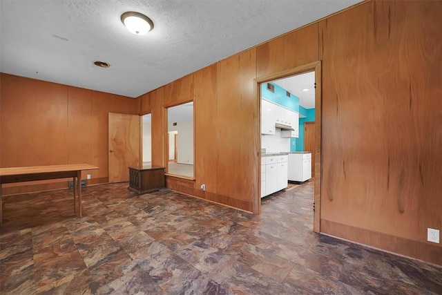 315 W 6th St, Cordell, OK 73632 - spare room featuring stone finish floors, wood walls, and a textured ceiling