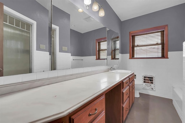 315 W 6th St, Cordell, OK 73632 - full bath with heating unit, tile walls, vanity, a bath, and wainscoting