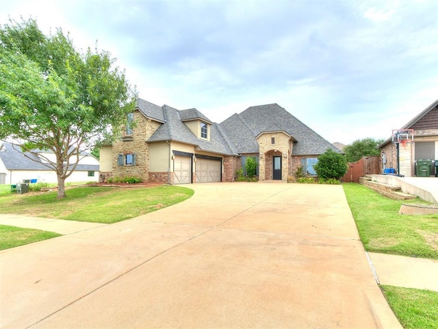 3009 Cordova Ct, Norman, OK 73072 - french country inspired facade featuring driveway, stone siding, a front lawn, brick siding, and roof with shingles