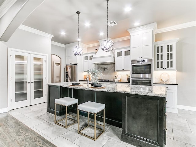 3009 Cordova Ct, Norman, OK 73072 - kitchen featuring stainless steel appliances, backsplash, crown molding, a large island with sink, and white cabinetry