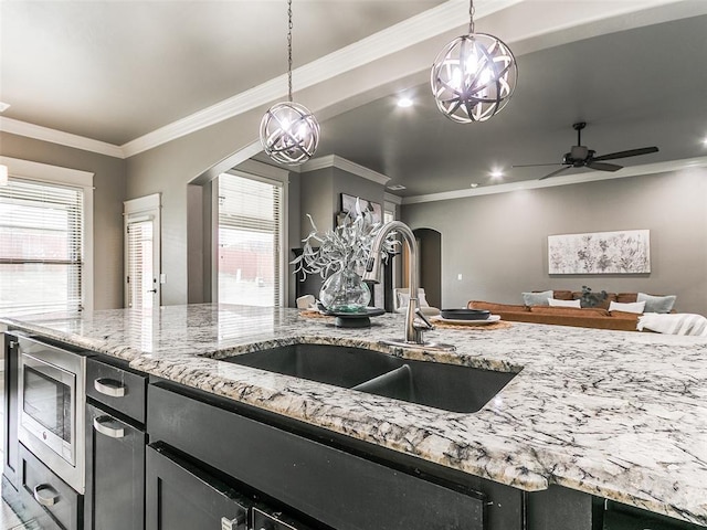 3009 Cordova Ct, Norman, OK 73072 - kitchen with stainless steel microwave, arched walkways, open floor plan, decorative light fixtures, and ornamental molding