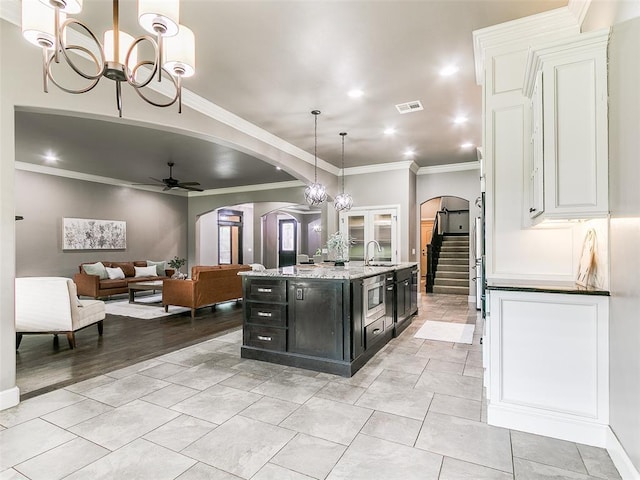 3009 Cordova Ct, Norman, OK 73072 - kitchen featuring arched walkways, ceiling fan, white cabinets, ornamental molding, and dark cabinetry