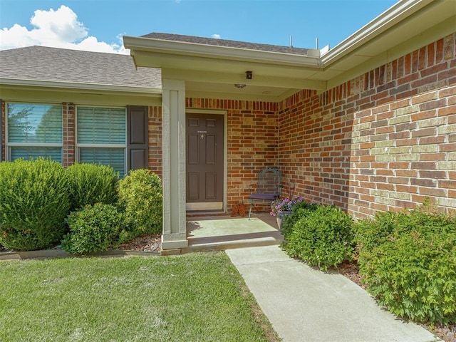 9505 SW 27th St, Oklahoma City, OK 73128 - doorway to property featuring brick siding, a lawn, and roof with shingles