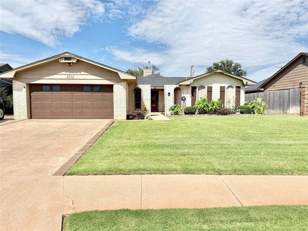 2512 Apache St, Altus, OK 73521 - ranch-style house with brick siding, concrete driveway, a garage, and a chimney