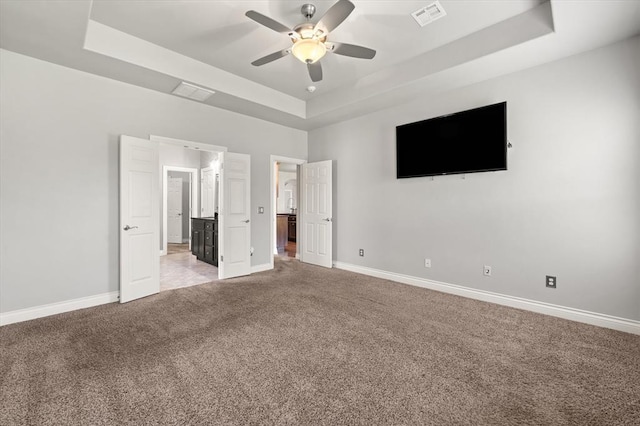 8309 NW 139th Ter, Oklahoma City, OK 73142 - unfurnished bedroom with a tray ceiling, light colored carpet, a ceiling fan, and connected bathroom